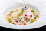 Cette assiette présente une composition culinaire complexe avec une variété d'aliments de différentes textures et couleurs.