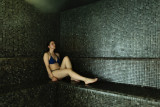 La photo montre l'intérieur d'un hammam avec une femme allongée sur un banc.