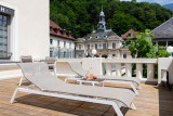 Cette terrasse privative offre un espace de détente avec des chaises longues confortables et une vue sur les thermes d'Uriage.